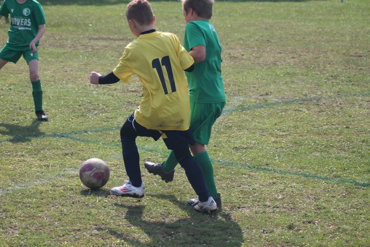A Southside Star player in yellow driving past a defender during a match