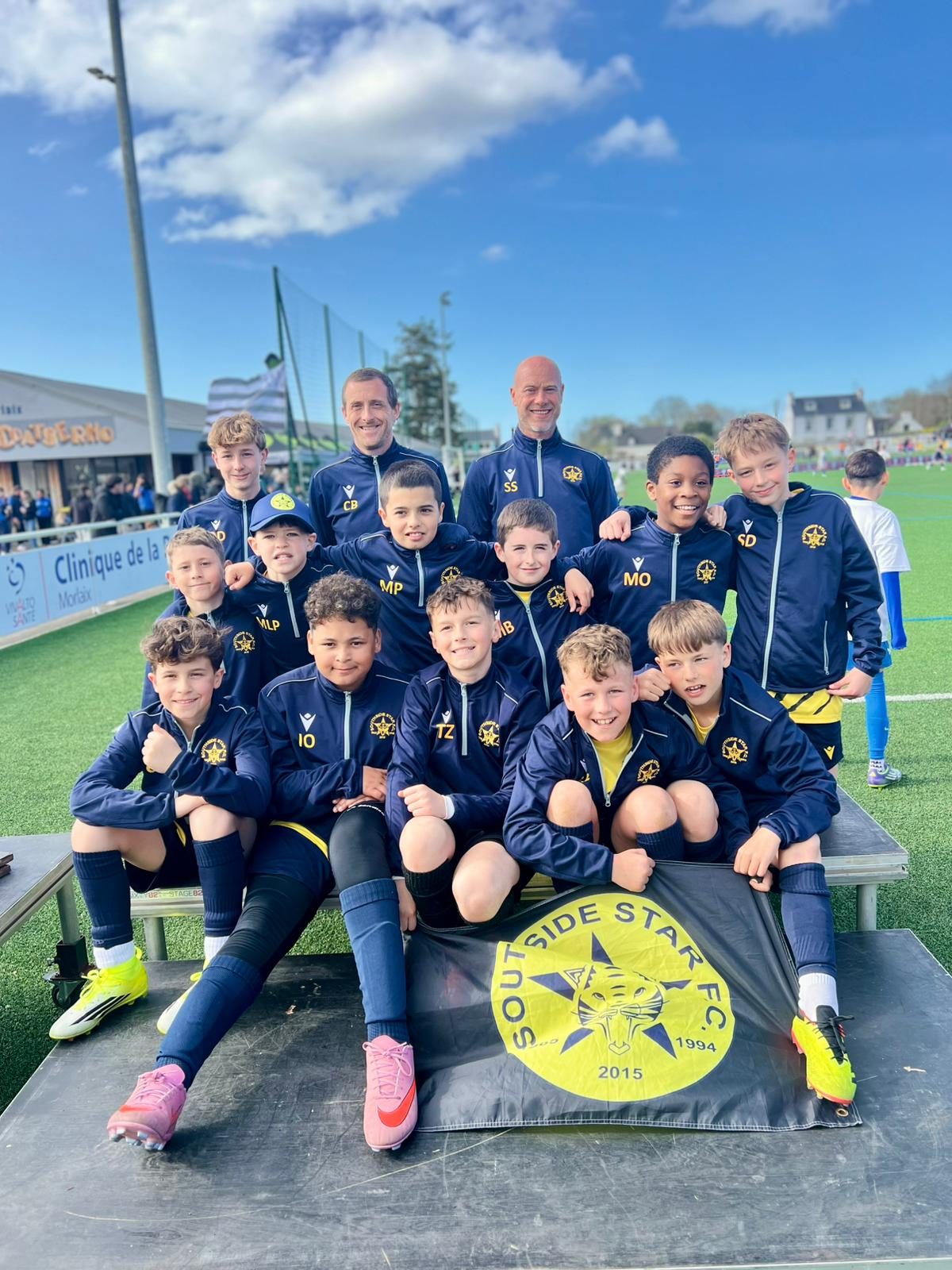 The Cheetahs squad in tracksuits with the Southside Star flag in the stand at the Morlaix Football Cup