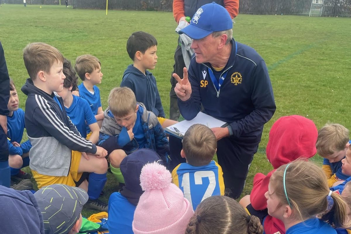 A Southside Star coach crouching down to talk to a group of Cubs players at training
