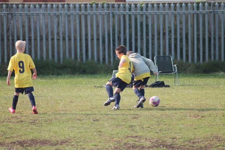 Two Southside Star players in yellow closing down the ball on a match day