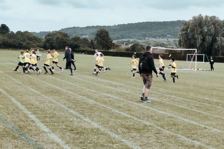Southside Star players running across a pitch with the Cotswold hills behind them